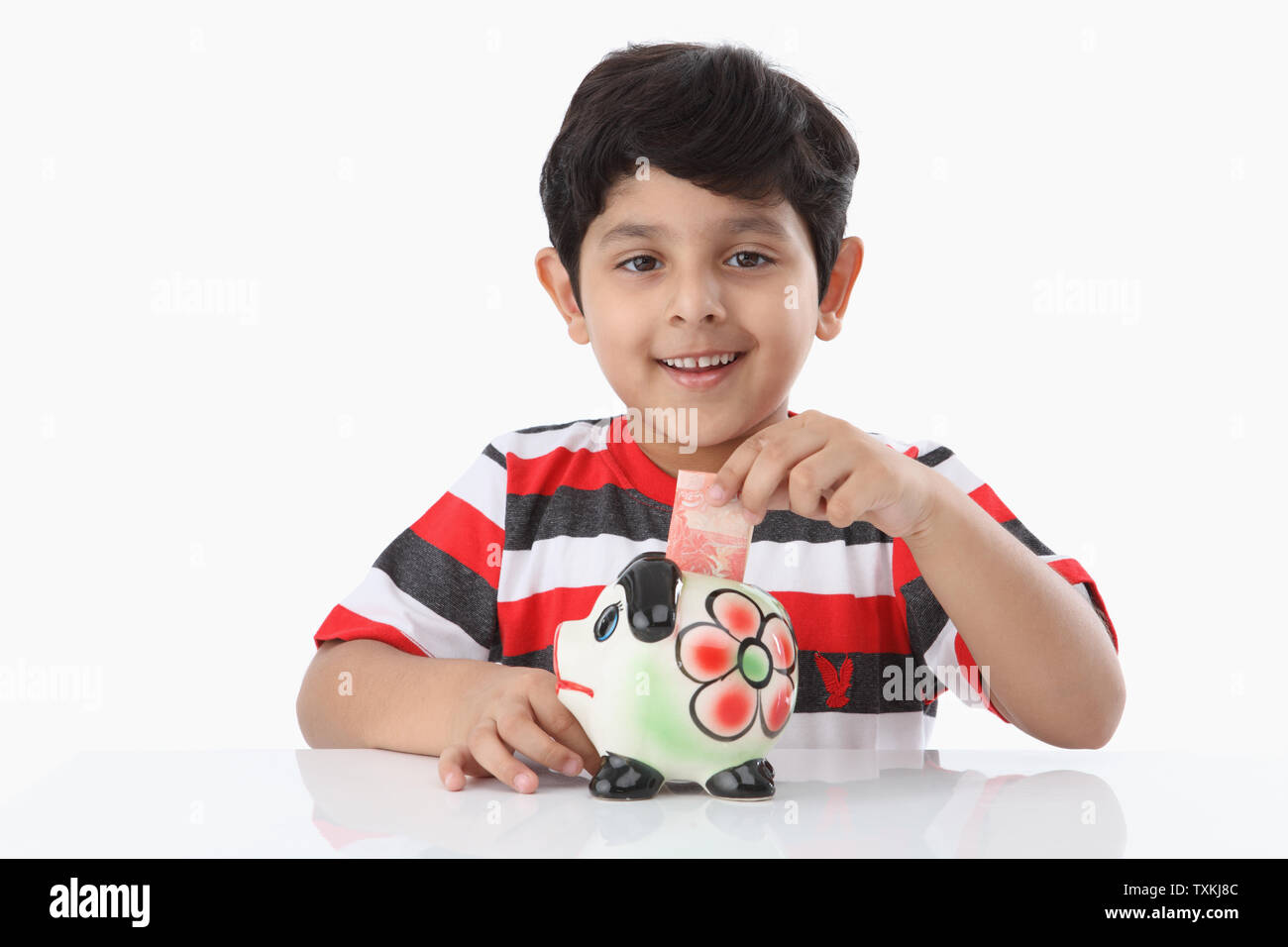 Boy putting banknote into a piggy bank Stock Photo - Alamy