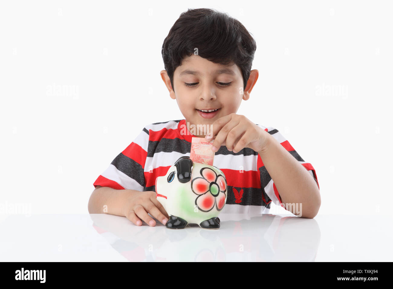 Boy putting banknote into a piggy bank Stock Photo - Alamy