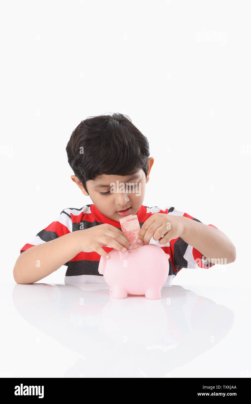 Boy putting banknote into a piggy bank Stock Photo - Alamy