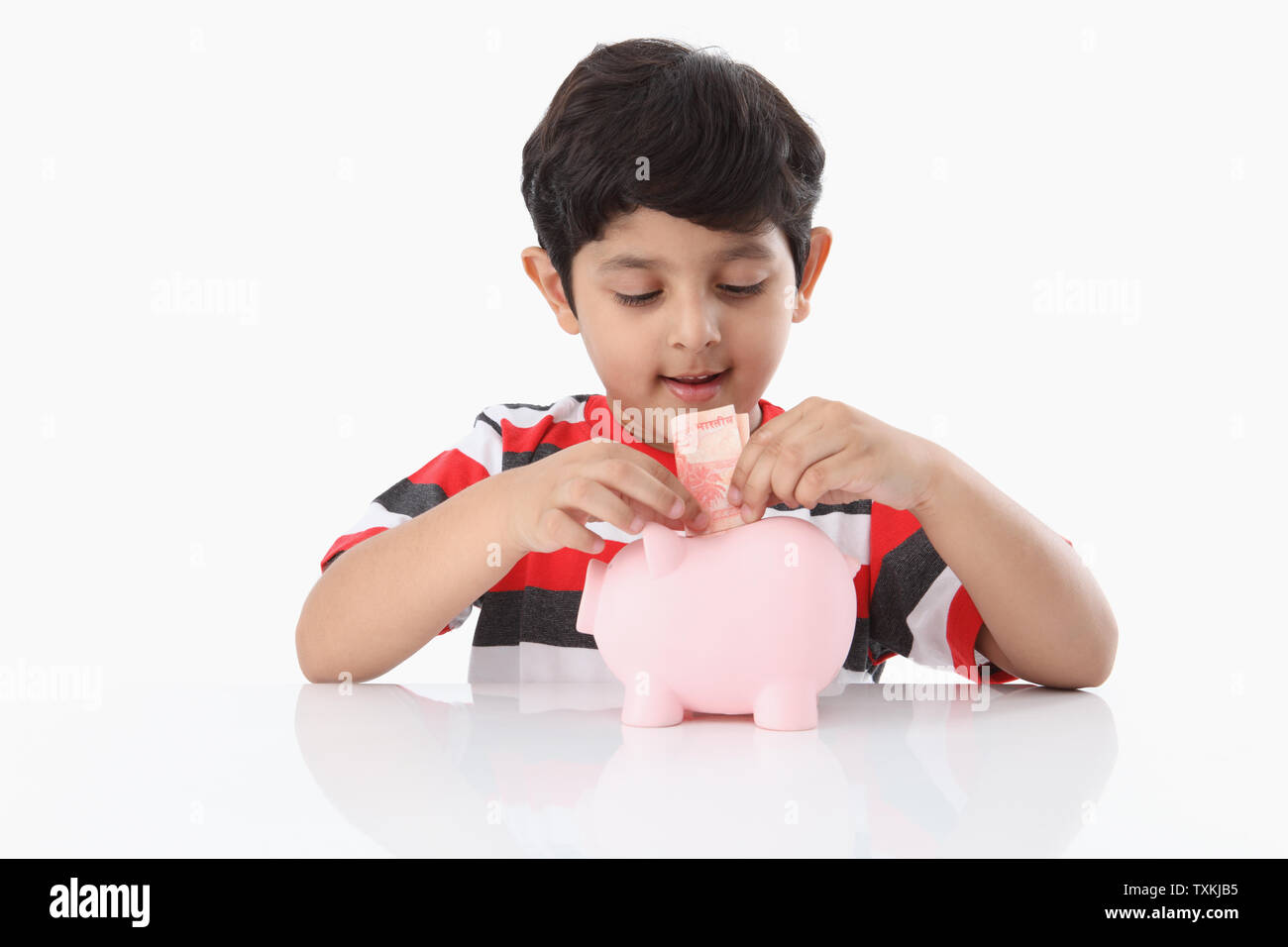 Boy putting banknote into a piggy bank Stock Photo - Alamy