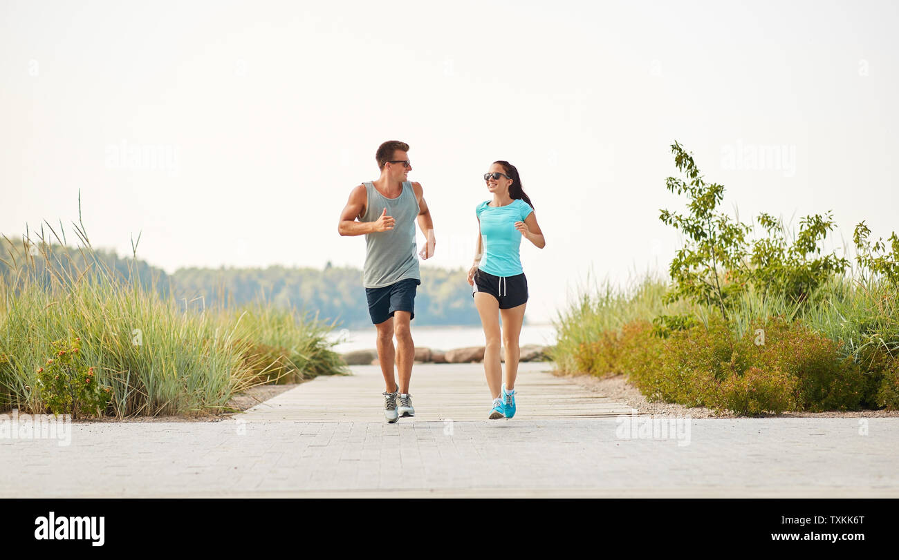 couple in sports clothes running along beach path Stock Photo - Alamy