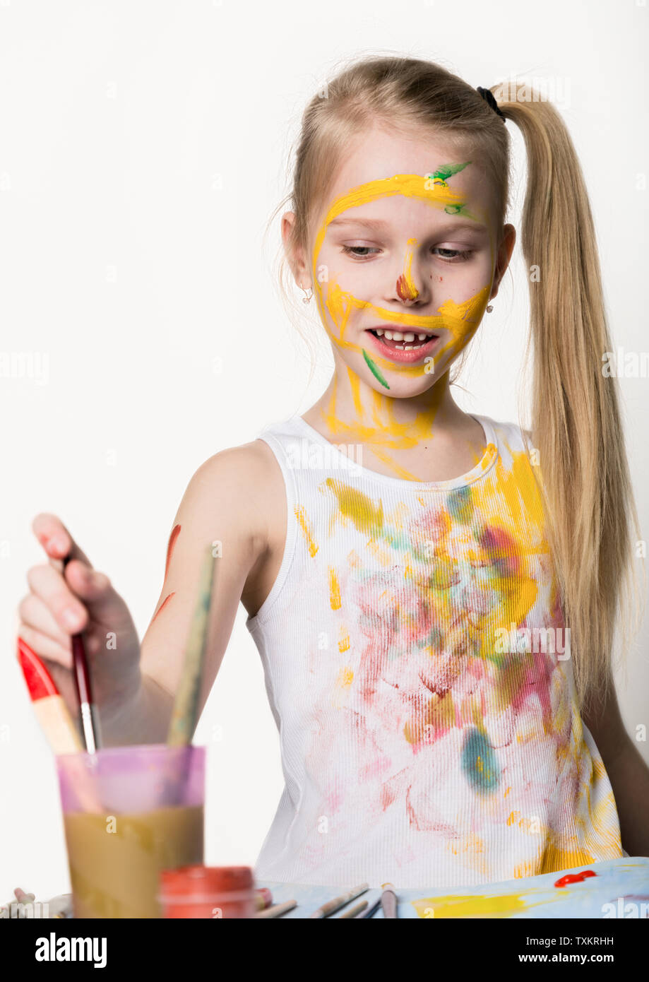 Cute little girl painter draws on the table and on himself on her ...
