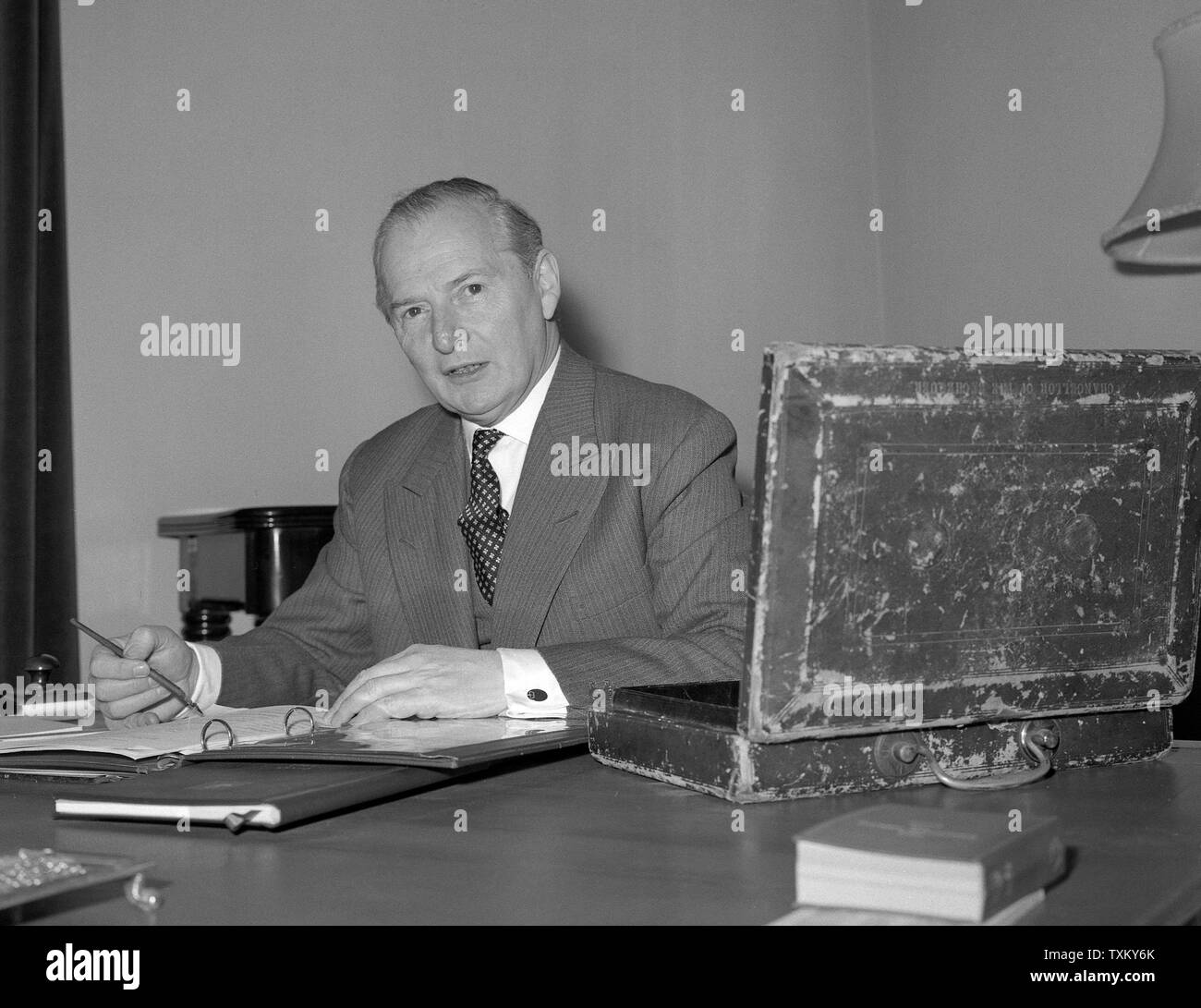 Selwyn Lloyd, Chancellor of the Exchequer, with the battered red despatch box, which holds the Budget secrets, working on his Budget at the Treasury in Whitehall, London. Stock Photo