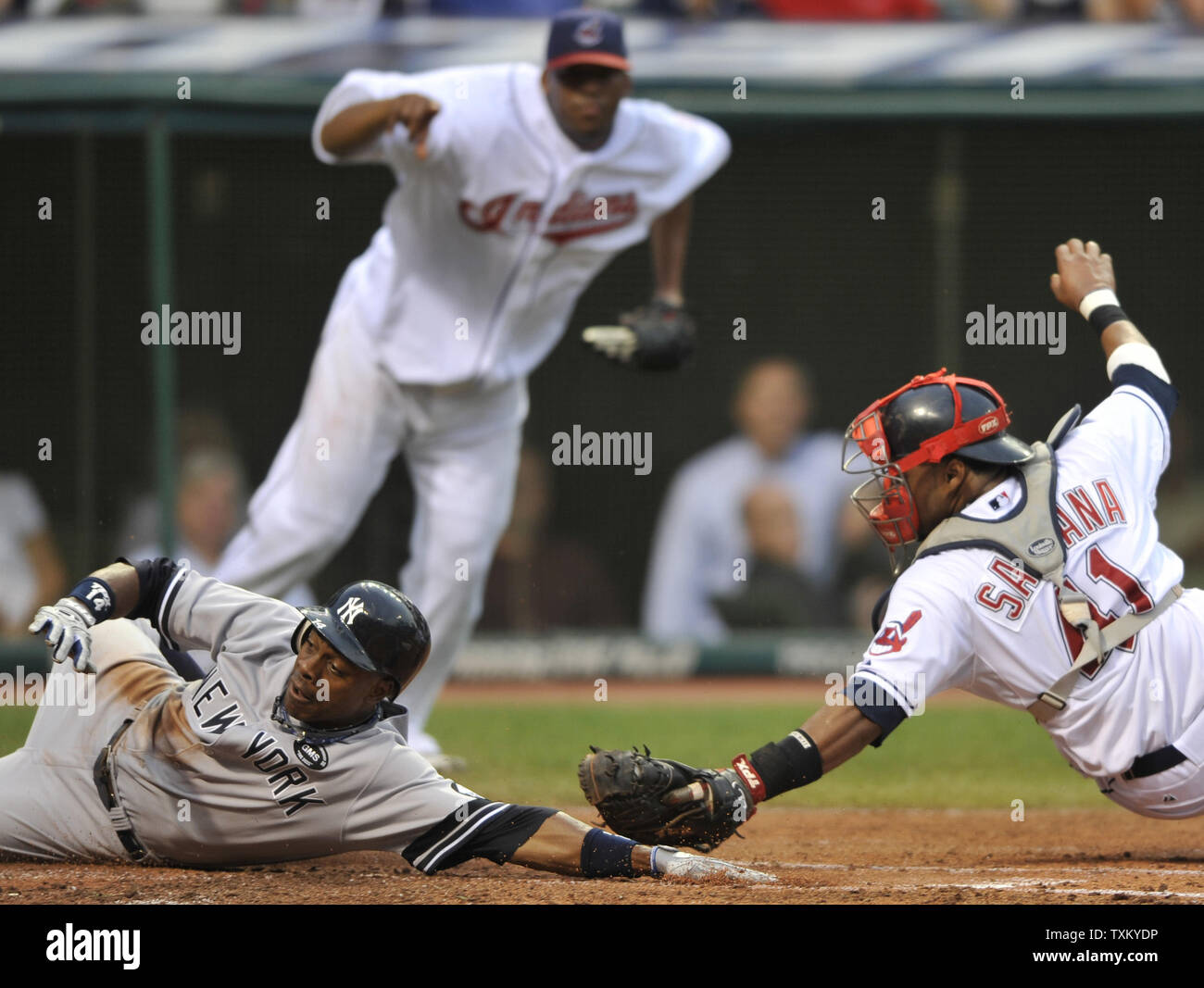New York Yankees' Curtis Granderson, left, scores before a tag from Cleveland catcher Carlos Santana, right, as Cleveland pitcher Fausto Carmona watches in the second inning of a baseball game at Progressive Field in Cleveland on July 28, 2010.  UPI/David Richard Stock Photo
