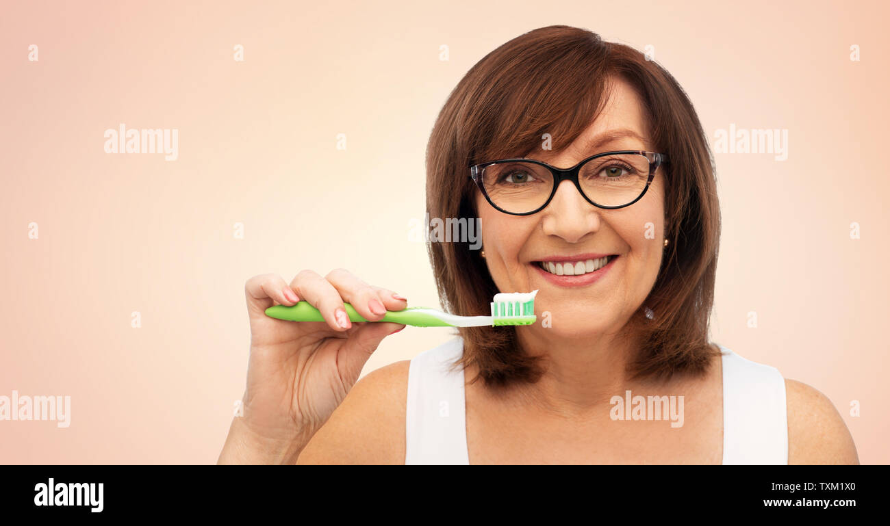 senior woman with toothbrush brushing her teeth Stock Photo