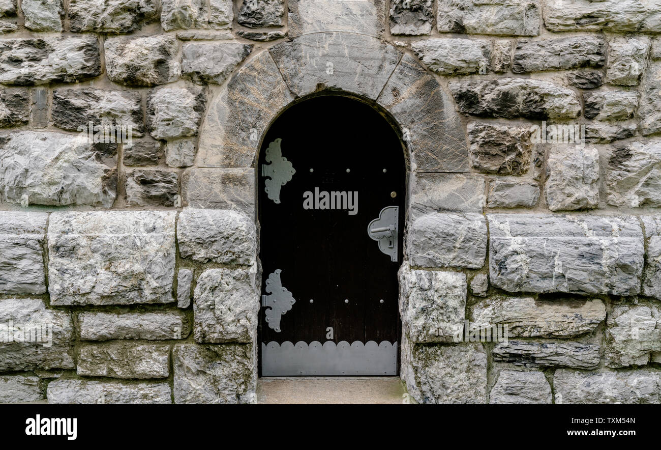 massive wooden door in a stone wall made of large granite blocks ...
