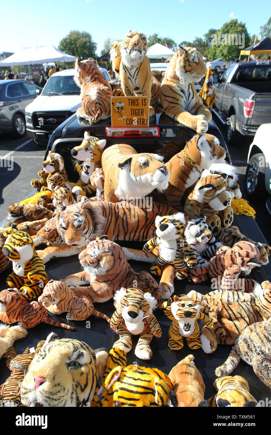 Stuffed tiger animals of all sizes sit on top of a pickup truck outside