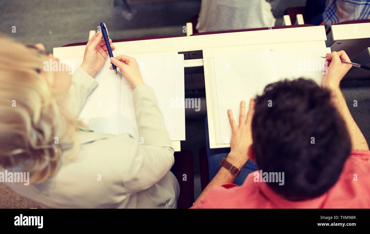 students with notebooks at exam or lecture Stock Photo