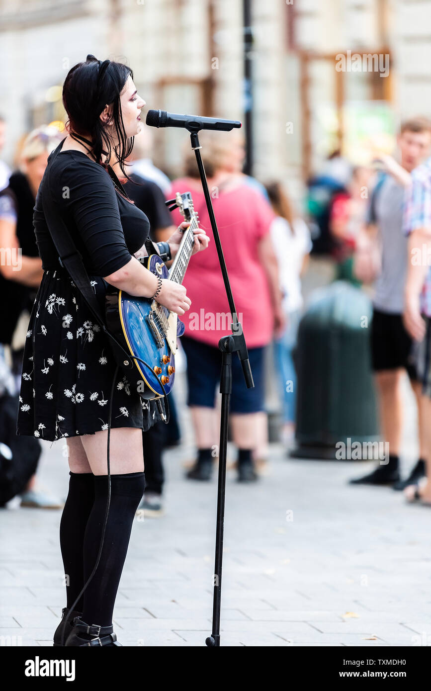 Lviv, Ukraine - July 30, 2018: Ukrainian city in old town market square with goth style woman playing guitar singing song in black dress Stock Photo
