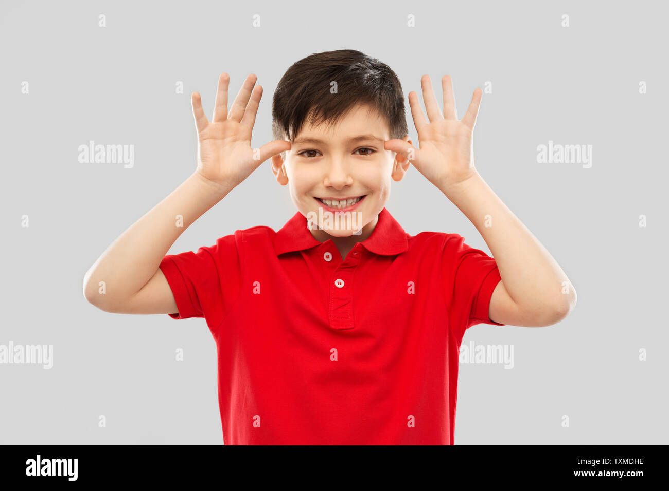 little boy in red t-shirt making big ears by hands Stock Photo