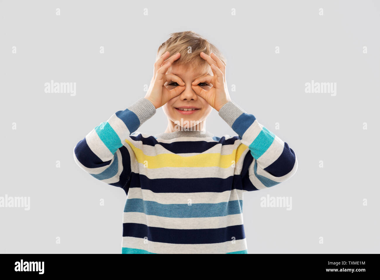 boy in pullover looking through finger glasses Stock Photo