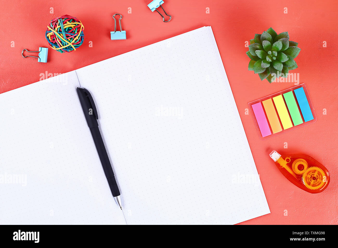 Blank notebook on the coral background, plant, keyboard. Top view, flat lay. Mockup, copy space. Stock Photo