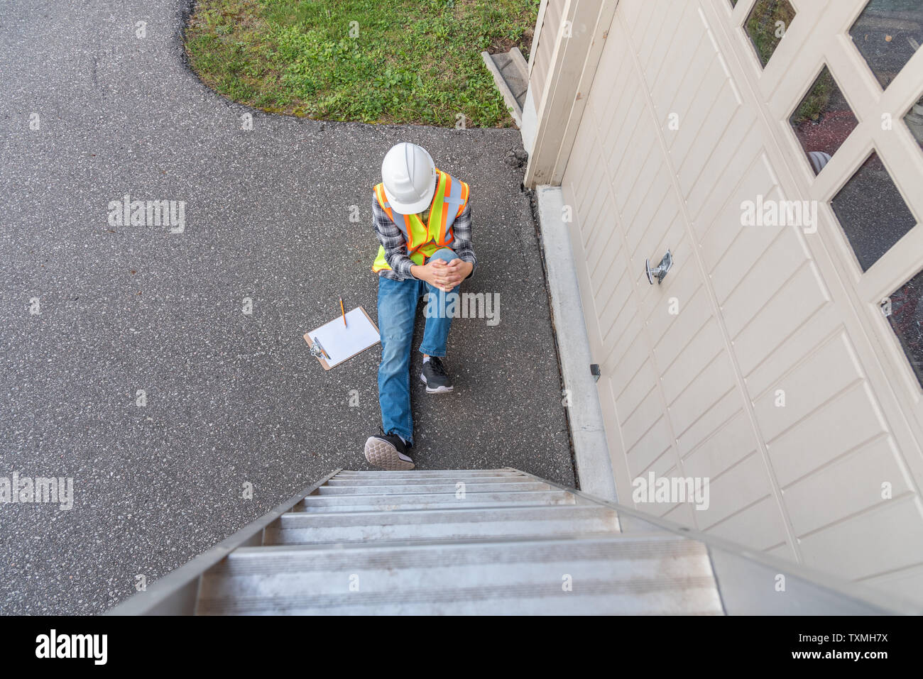 Injured architect sitting on the ground after having fallen off a ladder. Stock Photo
