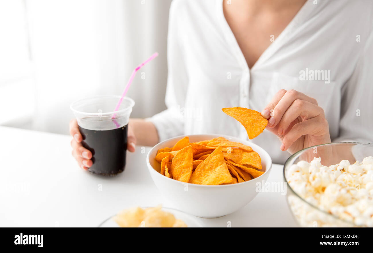 close up of woman eating corn nachos with cola Stock Photo