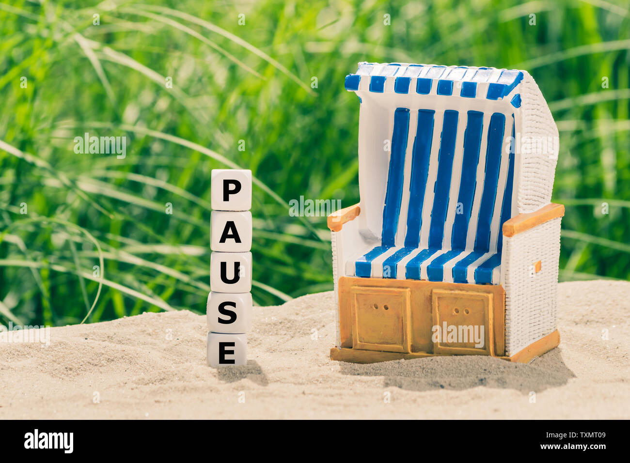 Concept for the summer break. Dice form the German word 'Pause' ('break' in English) next to a beach chair . Stock Photo