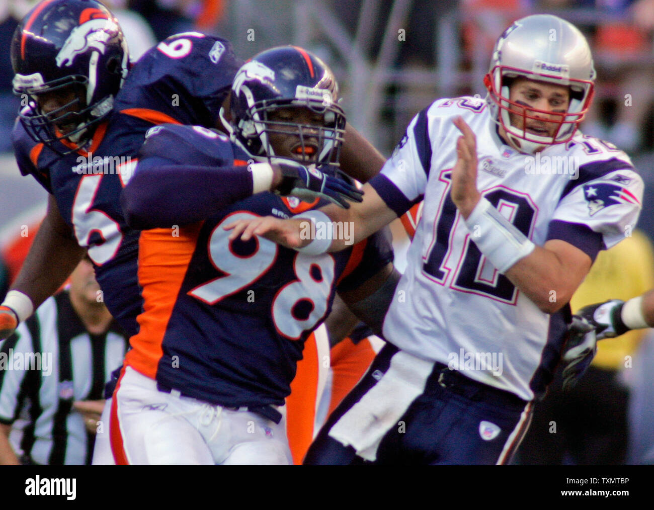 New England Patriots quarterback Tom Brady (R) behind his center Russ  Hochstein (C) faces off against Denver Broncos tackle Gerard Warren (L)  during the AFC divisional playoff game at Invesco Field in