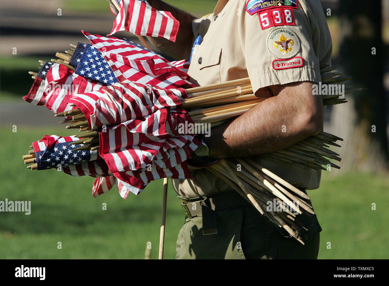 A Scoutmaster carries bundles of American Flags to place for Memorial Day observances at Fort Logan National Cemetery in Denver May 27, 2006.  Fort Logan National Cemetery was created in 1889 and was named after General John A. Logan who issued General Order No. 11 that established Decoration Day on May 30th which later became a National Holiday called Memorial Day.   (UPI Photo/Gary C. Caskey) Stock Photo