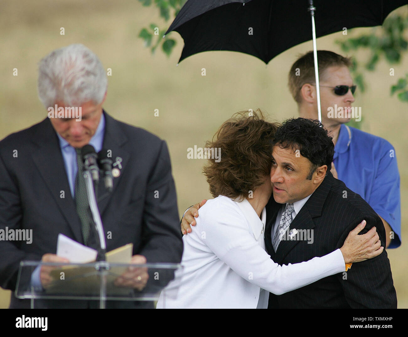 Columbine high school principal Frank DeAngelis (second from right) hugs  Dawn Anna Beck, mother of Columbine victim Lauren Townsend, with former  President Bill Clinton at the podium at the official Columbine memorial