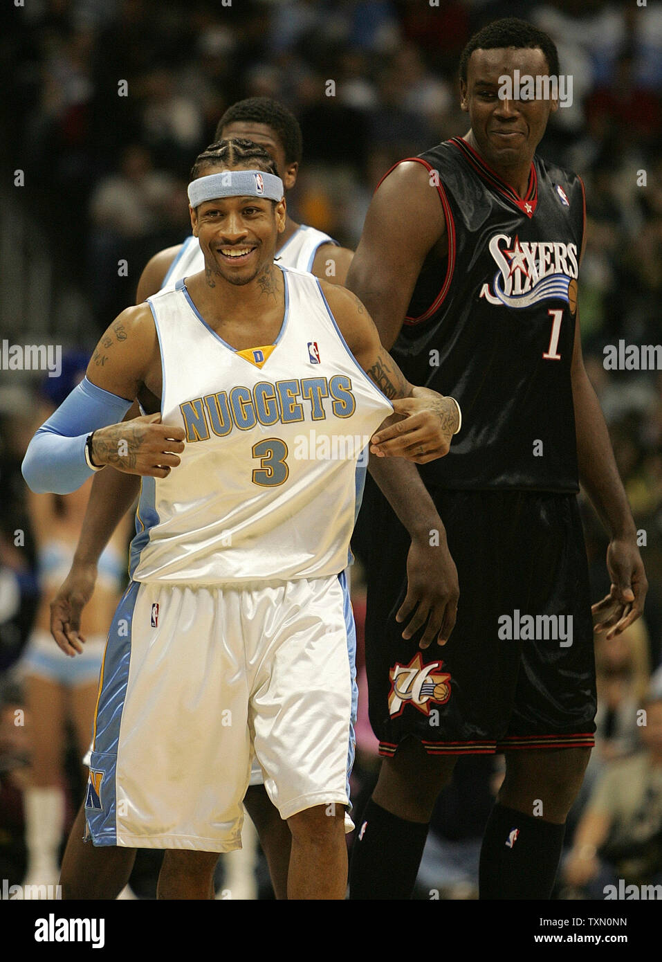 Denver Nuggets guard Allen Iverson (L) fluffs his Nuggets jersey after  greeting former treammate Samuel Dalembert (R) prior to tipoff at the Pepsi  Center in Denver January 2, 2007. Iverson is facing
