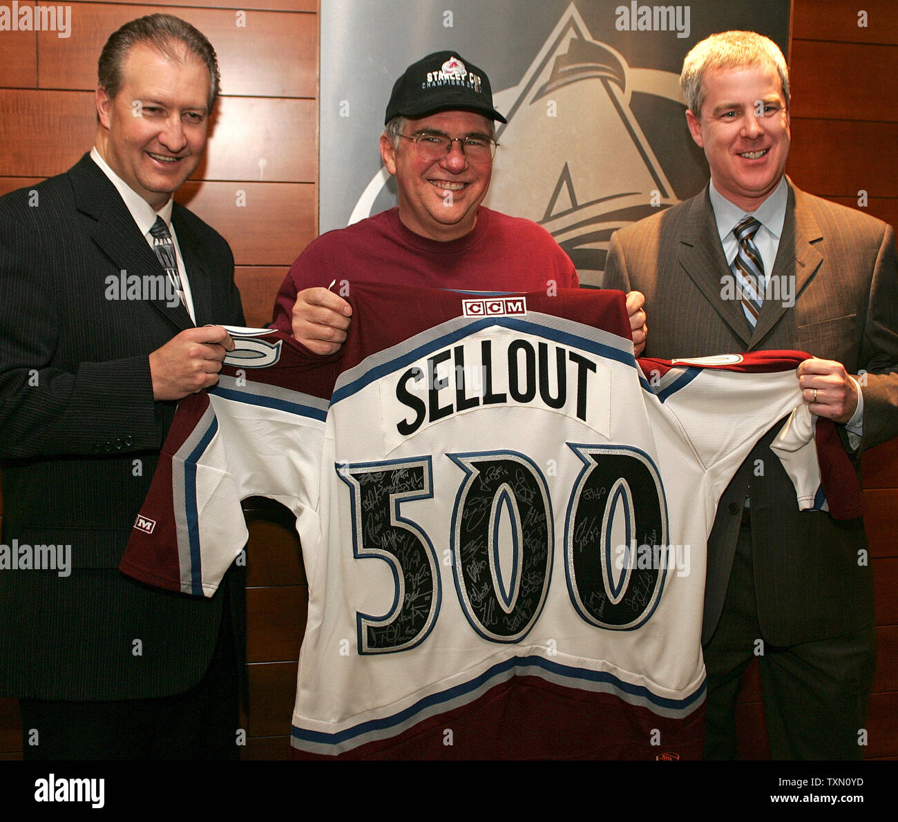 Colorado Avalanche Executive Vice President and General Manager Francois Giguere (R) and Kroenke Sports Enterprises Executive Vice President and Chief Marketing Officer Paul Andrews (L) pose with the 500th fan entering the Pepsi Center, Ray Sherrier of Colorado Springs, the lucky recipient of a signed team jersey commemorating the Avalanche's 500th sellout at the Pepsi Center in Denver January 20, 2007.  All members of the Avalanche signed the jersey presented to  Sherrier.  (UPI Photo/Gary C. Caskey) Stock Photo
