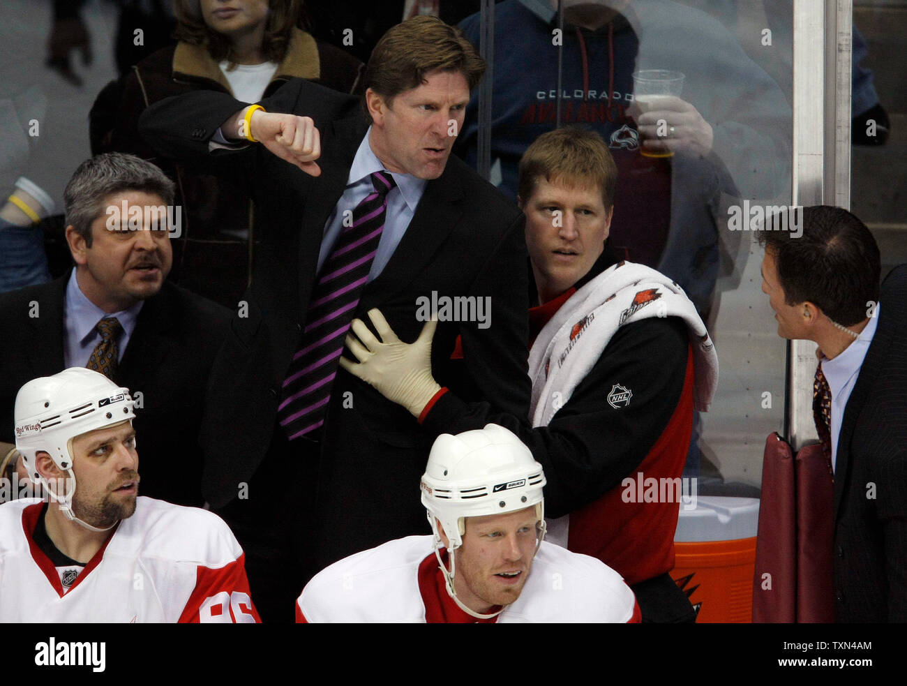 Detroit Red Wings head coach Mike Babcock (C) struggles while being  restrained talking to Colorado Avalanche assistant coach Tony Granato (R)  during the beginning of the third period at the Pepsi Center