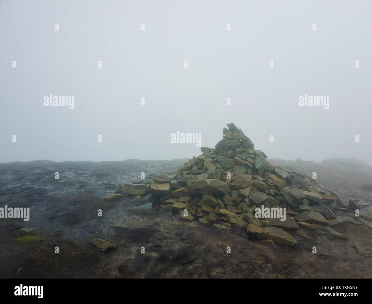 Pile of stones on the muddy ground surrounded by mist on the top of Hoverla peak in Carpathian Mountains, Ukraine. Stock Photo