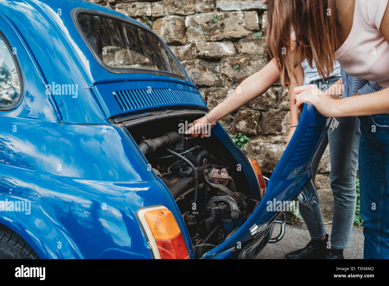 Friends fixing stalled car in countryside Stock Photo