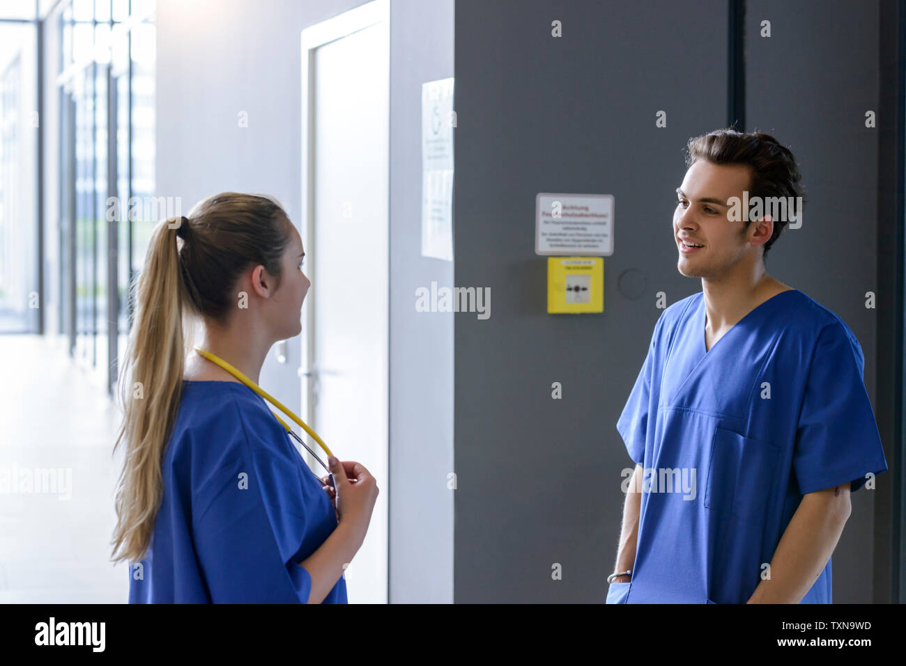 Male and female junior doctors chatting in hospital corridor Stock Photo
