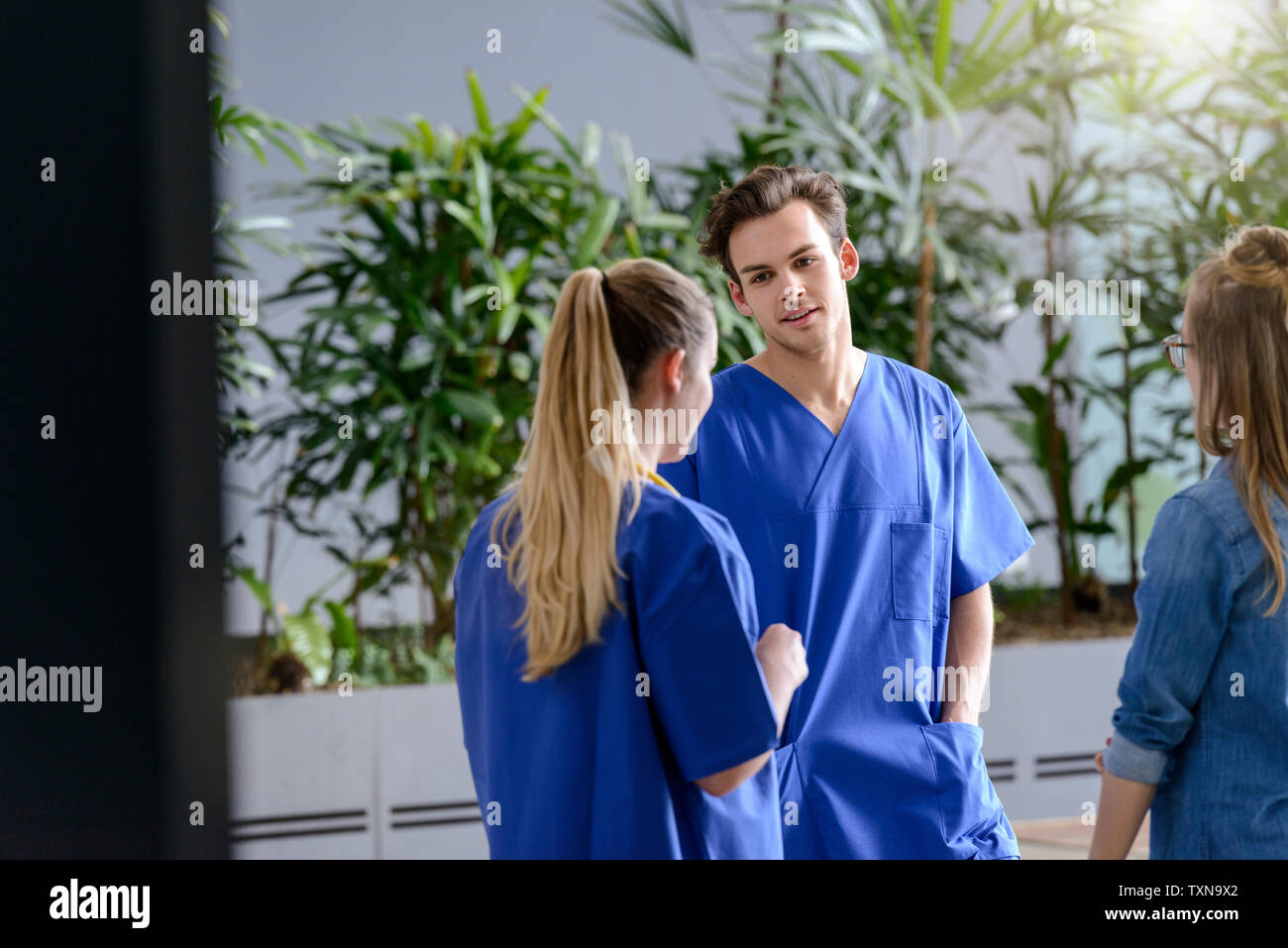 Male and female junior doctors chatting outside hospital Stock Photo