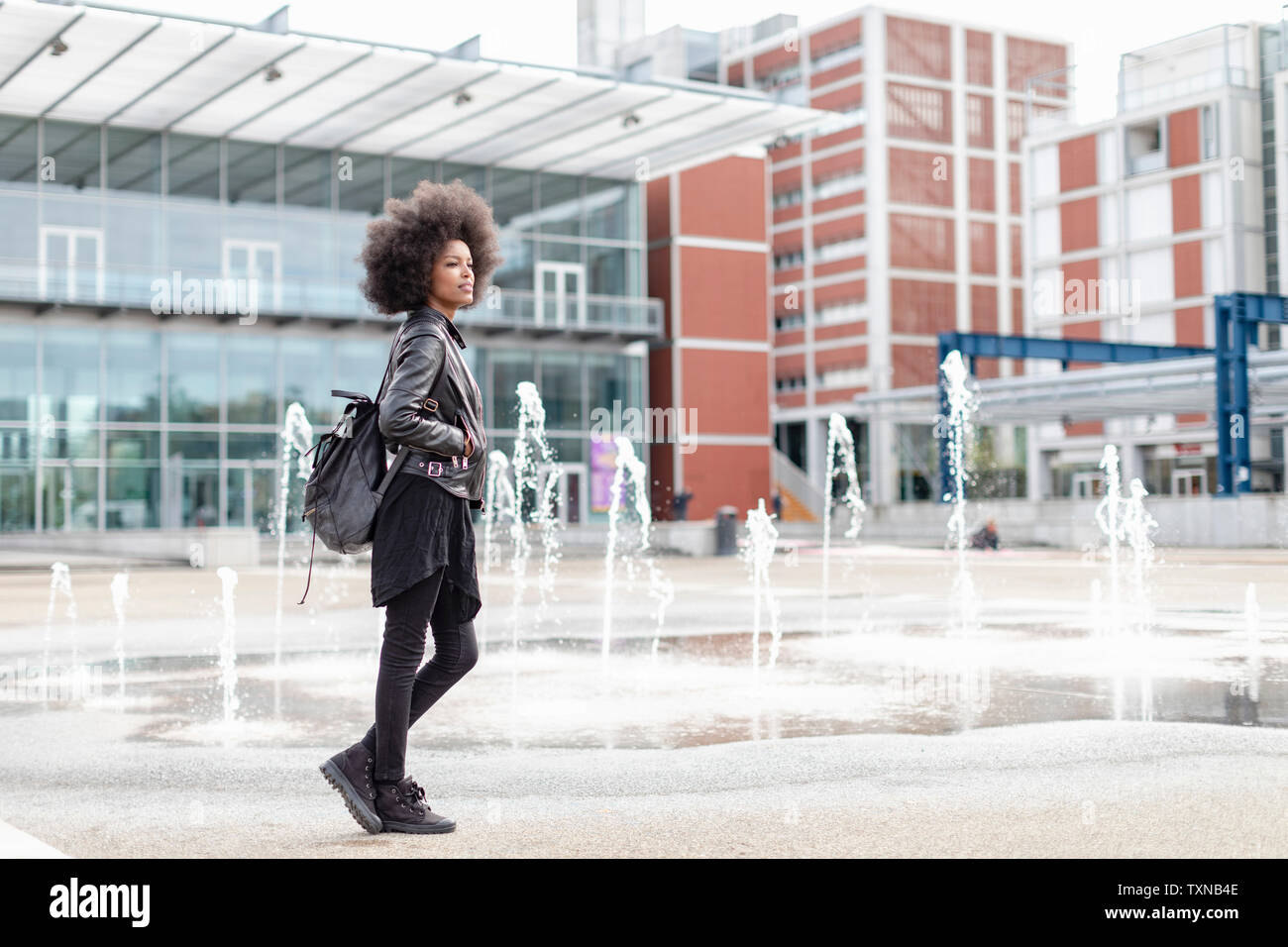 Cool young woman with afro hair on city concourse, full length Stock Photo