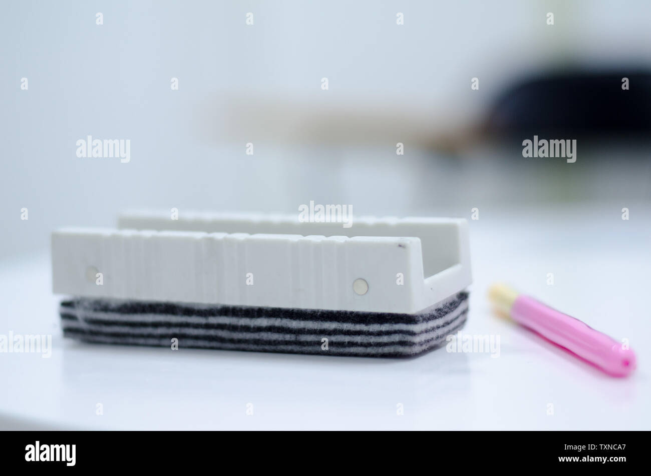 A whiteboard, brush, eraser and a red pen on the desk in the classroom