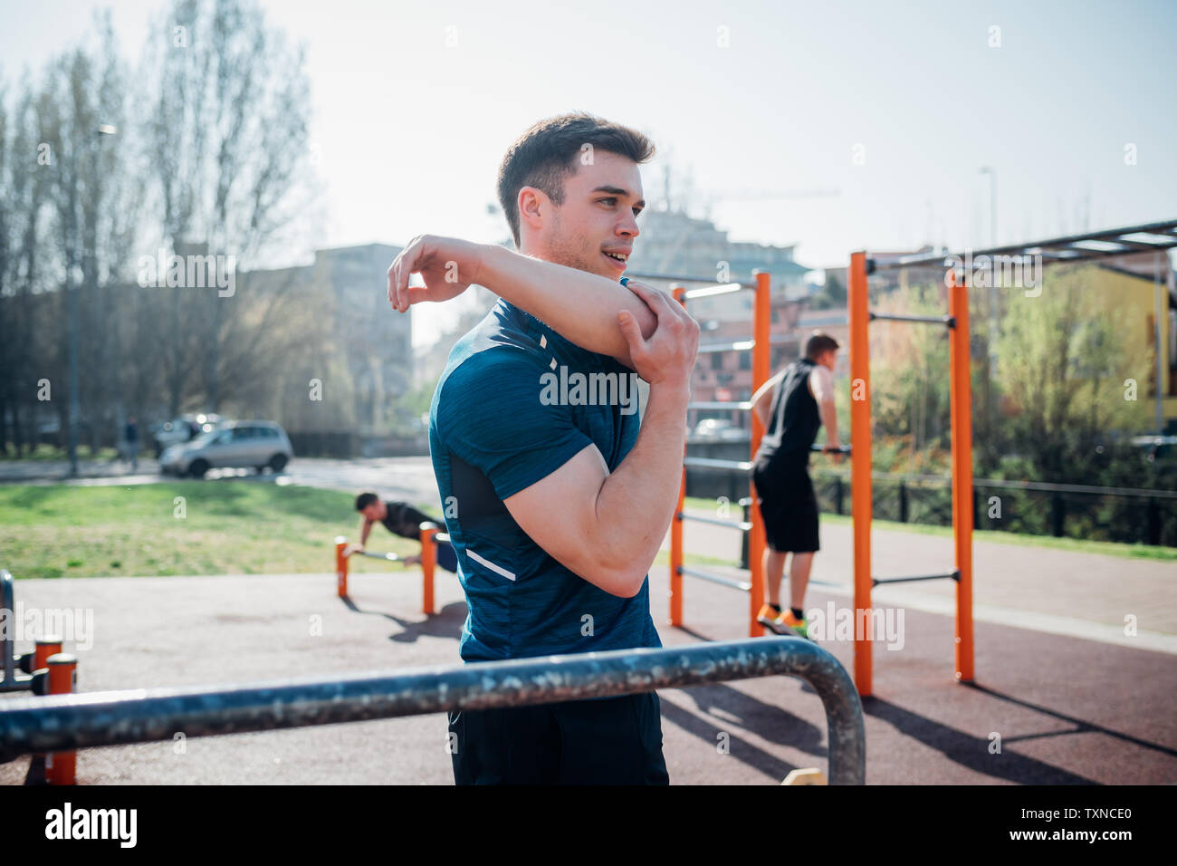 Calisthenics at outdoor gym, young man stretching arm Stock Photo