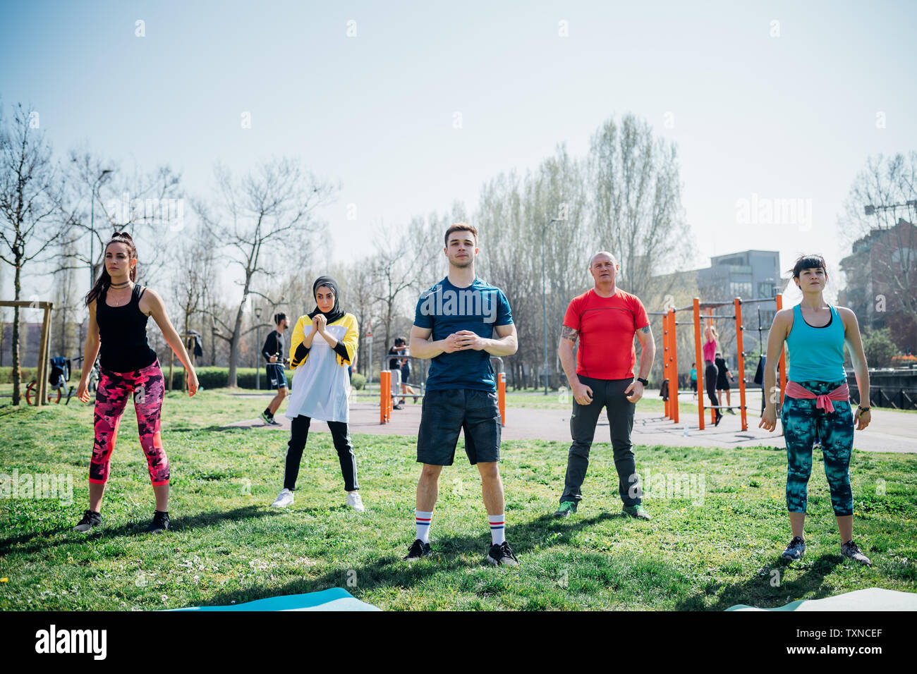 Calisthenics class at outdoor gym, women and men practicing yoga Stock Photo