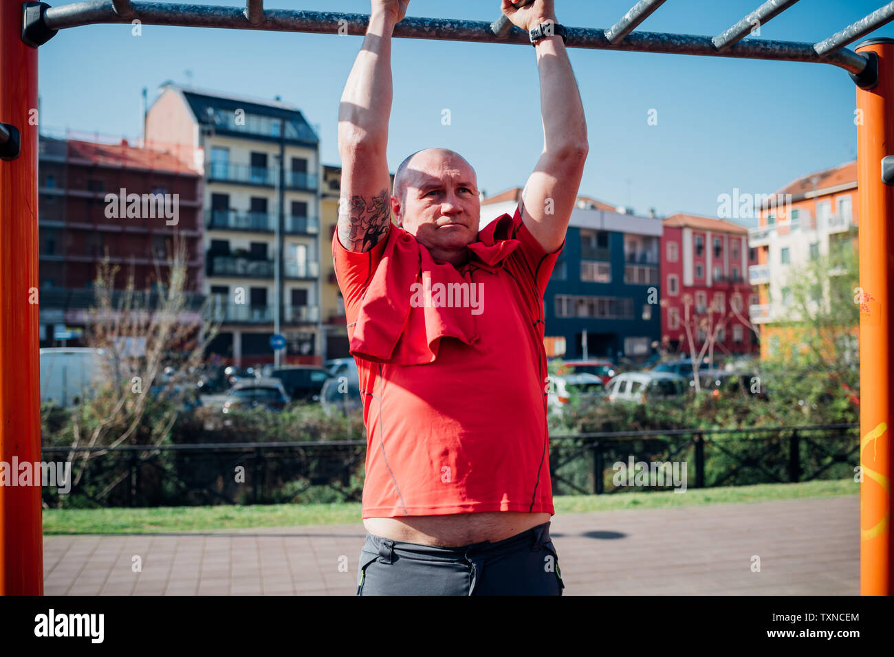 Calisthenics at outdoor gym, mature man doing pull up on exercise equipment Stock Photo