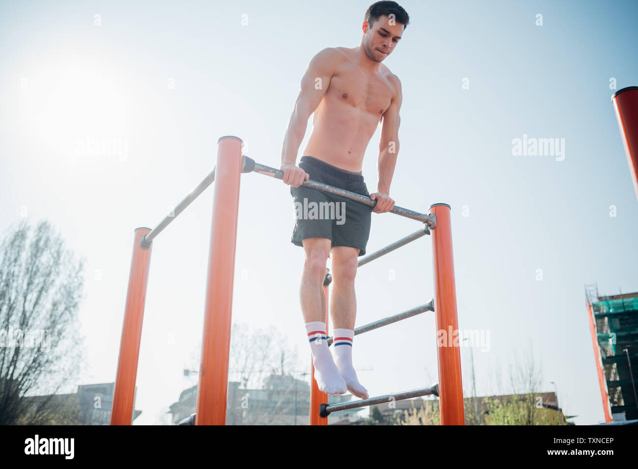 Calisthenics at outdoor gym, bare chested young man doing push up on ...