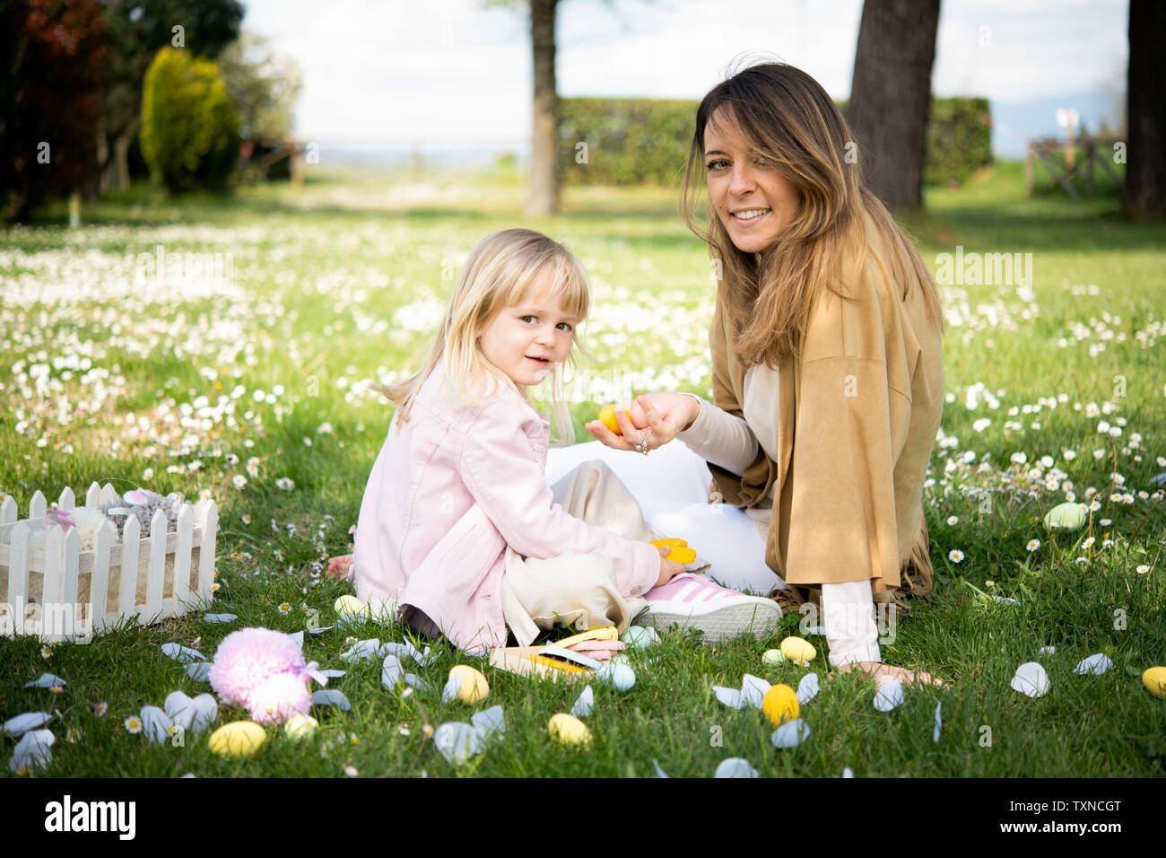 Mother and daughter relaxing in wildflower field after easter egg hunt, portrait, Arezzo, Tuscany, Italy Stock Photo
