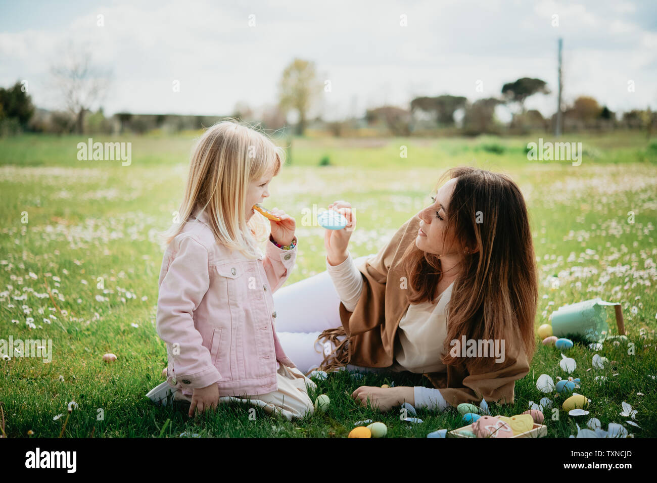 Mother and daughter relaxing in wildflower field after easter egg hunt, Arezzo, Tuscany, Italy Stock Photo