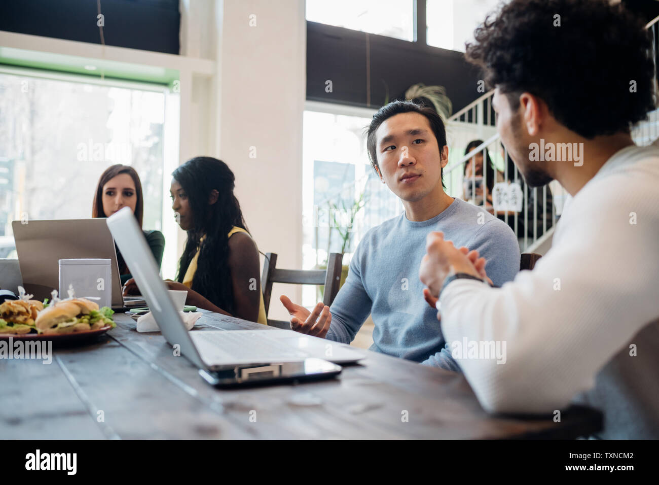 Young businessmen having discussion at cafe table Stock Photo