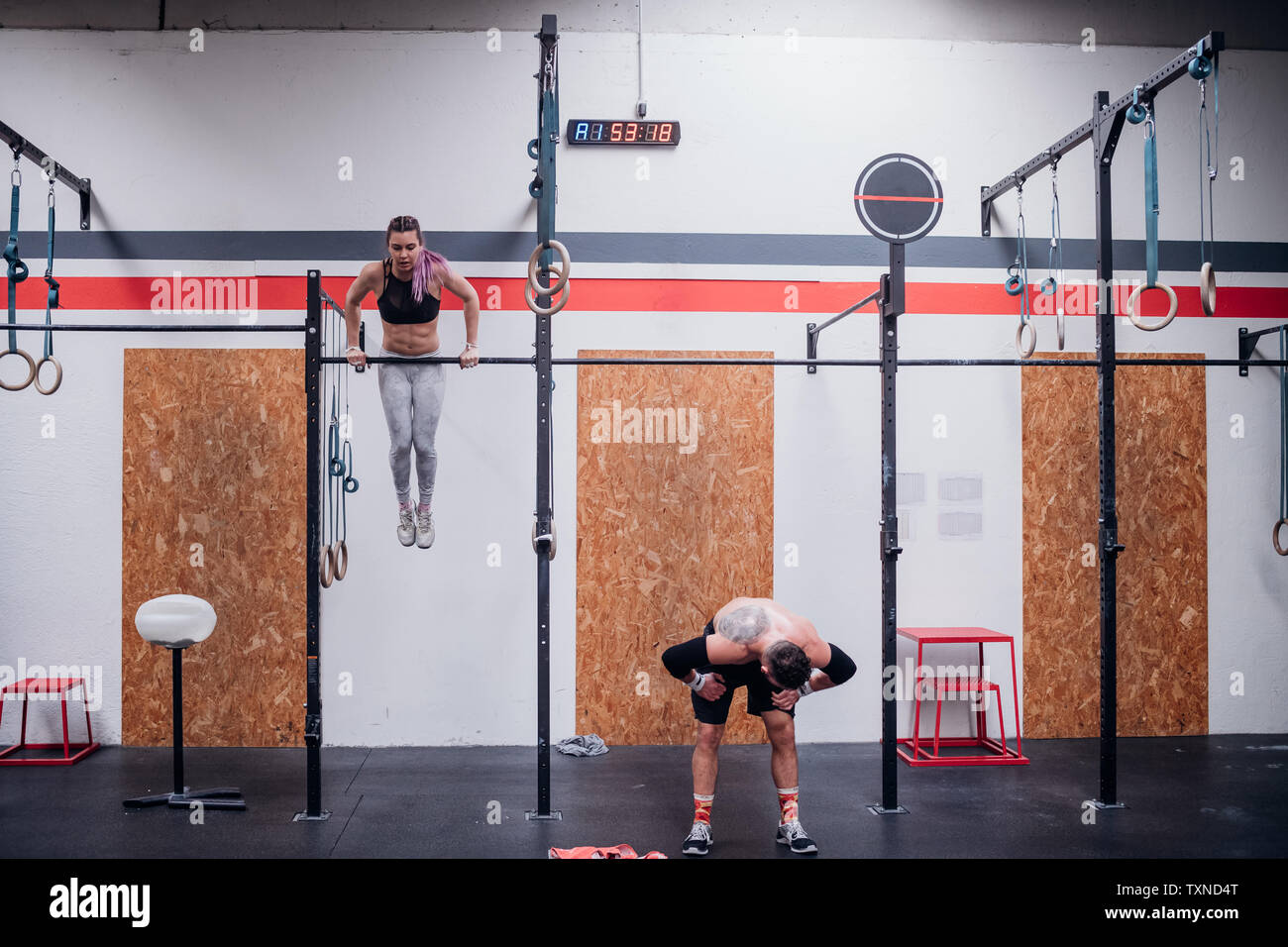 Young woman and man training, on exercise bars in gym Stock Photo - Alamy