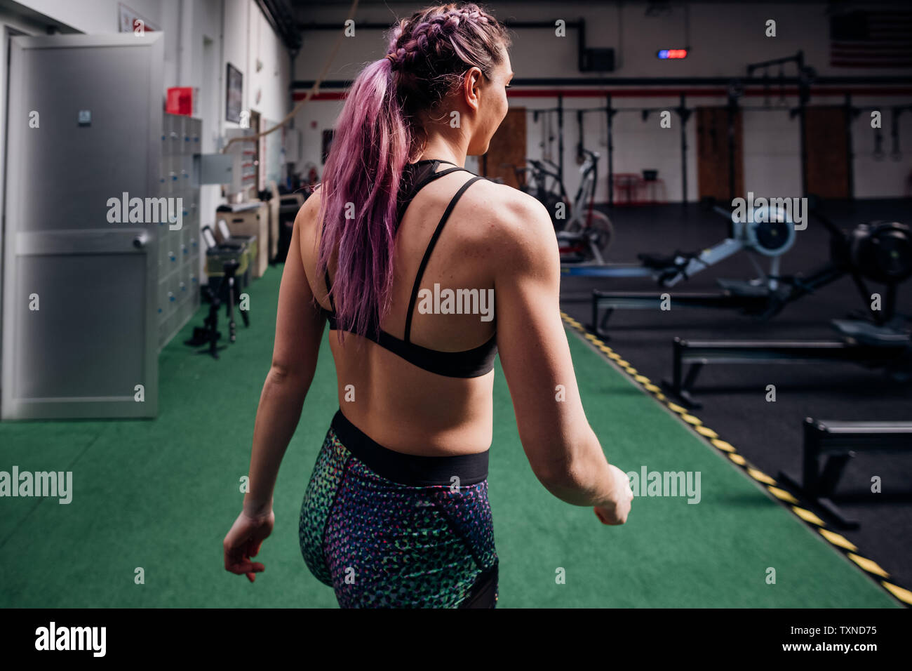 Young woman with plaited purple hair walking through gym Stock Photo