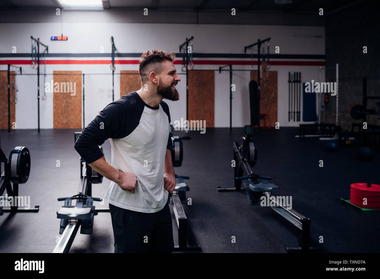 Young bearded man training, standing with hands on hips in gym Stock Photo