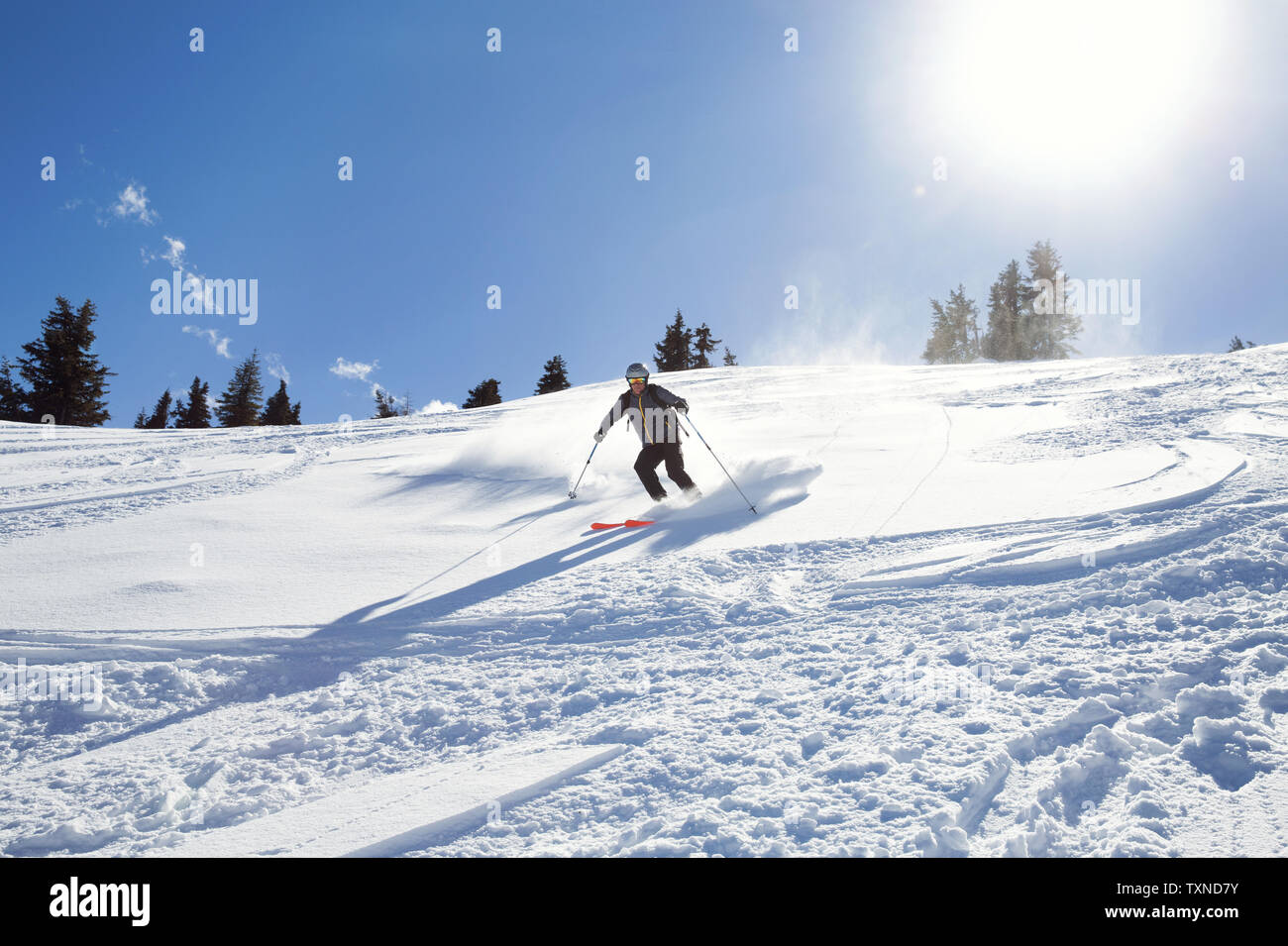 Mature man skiing down sunlit snow covered mountain,  Styria, Tyrol, Austria Stock Photo