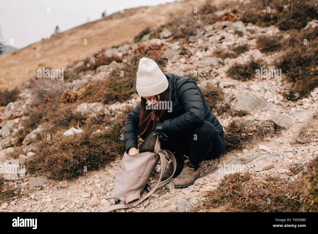 Trekker searching in bag, Trossachs National Park, Canada Stock Photo