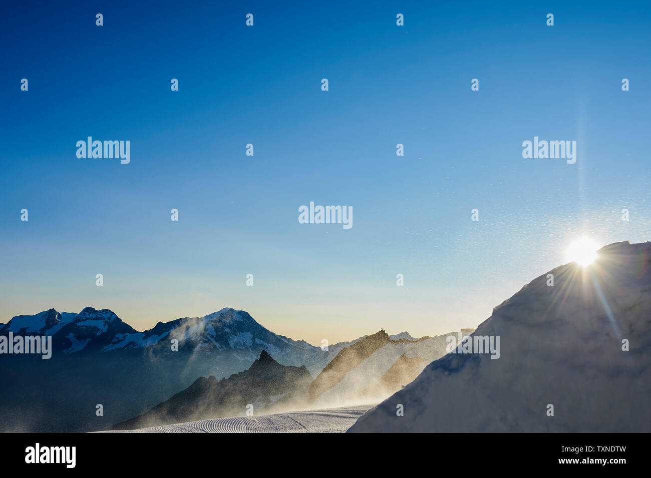Sun peeking behind mountain, Saas-Fee, Valais, Switzerland Stock Photo