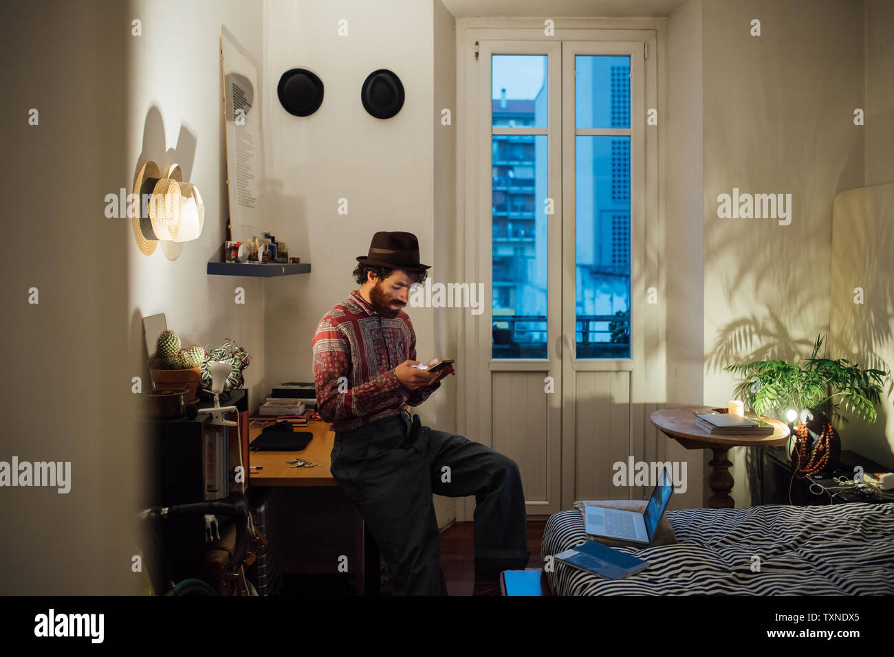 Bearded young man using smartphone on bedroom table Stock Photo
