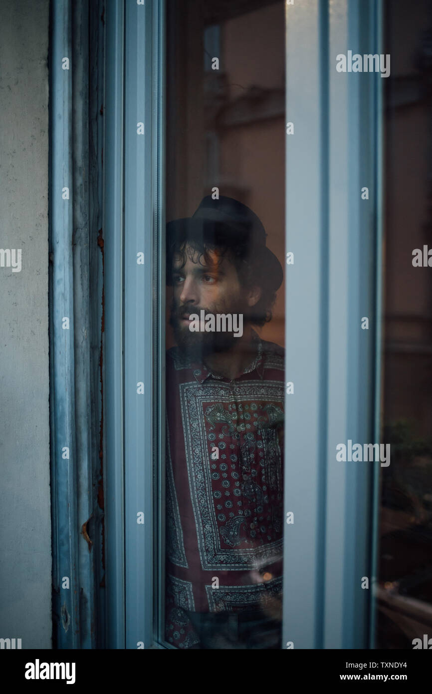 Bearded young man in deep thought by window Stock Photo