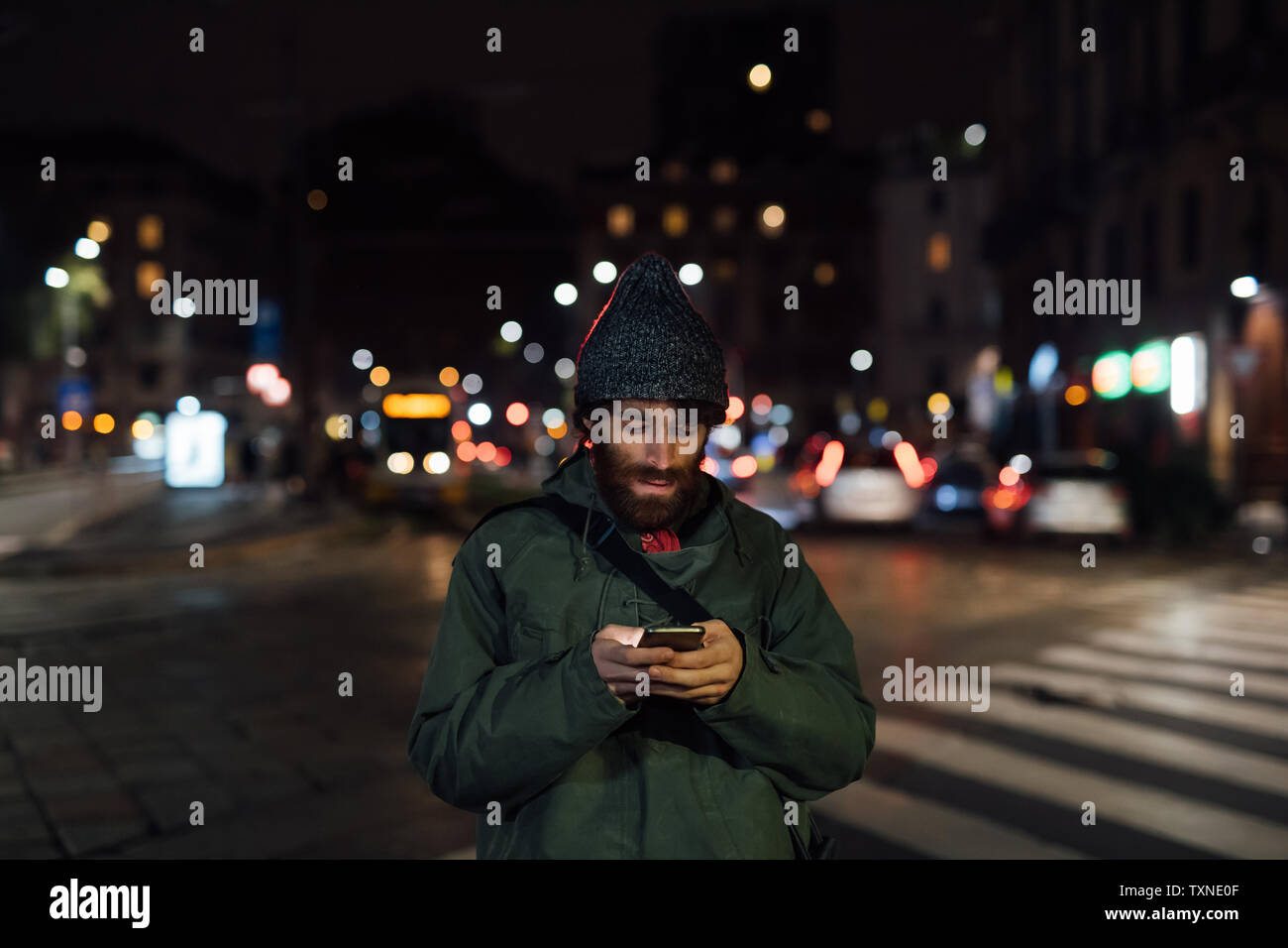 Bearded young man using smartphone on street Stock Photo