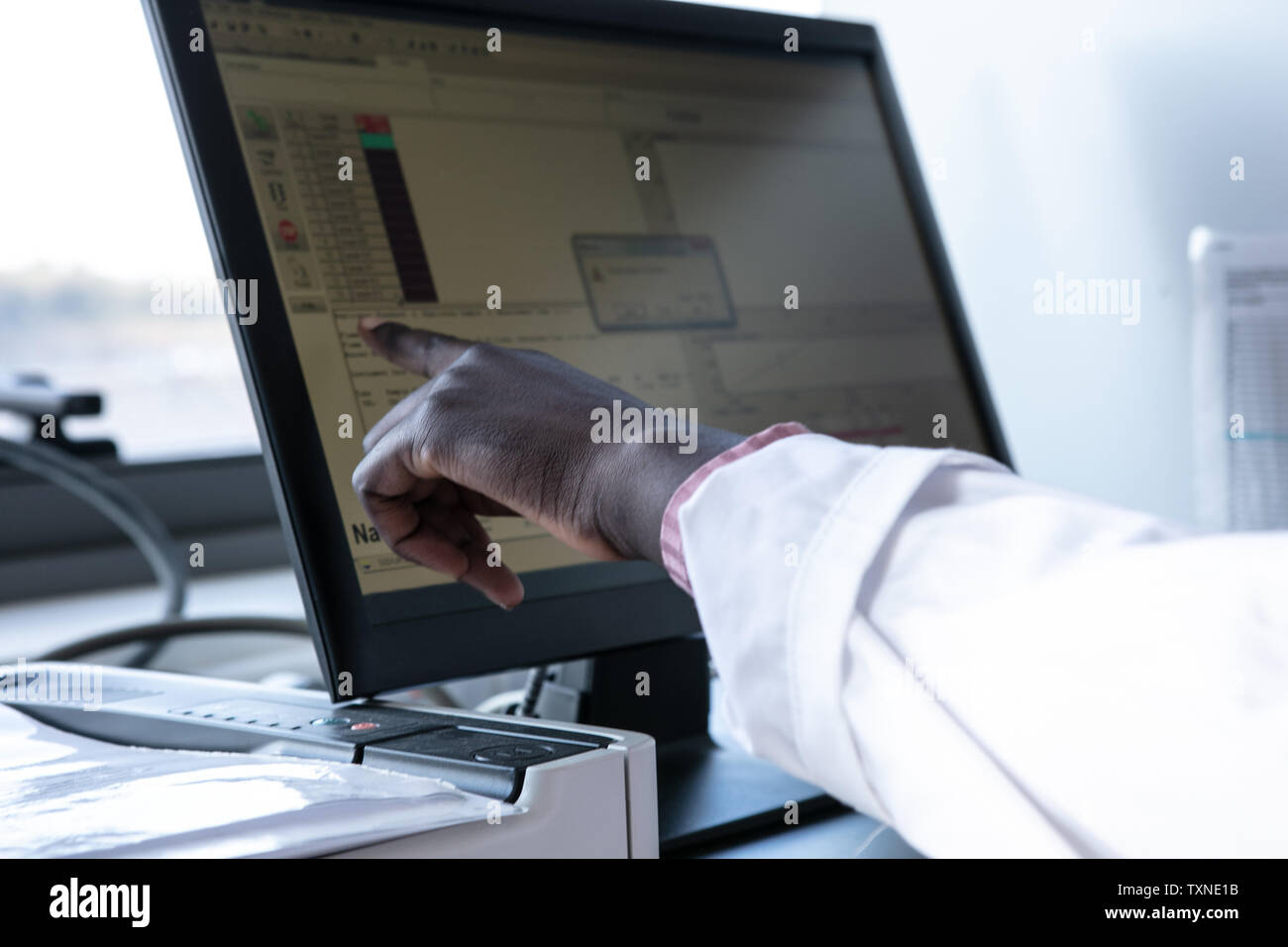 Young female scientist pointing at computer screen in laboratory ...