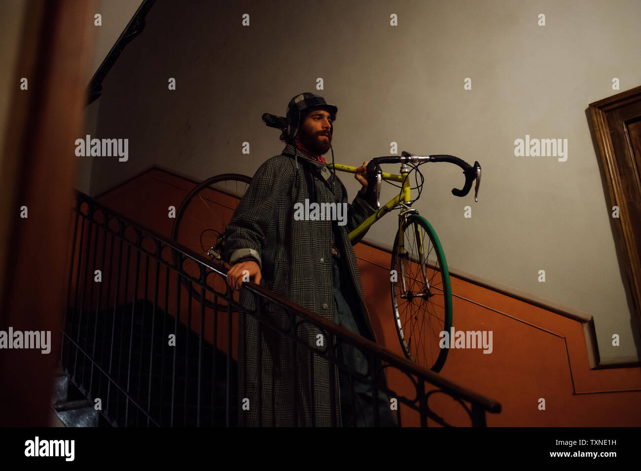 Bearded young man with bicycle over shoulder going down stairway Stock Photo