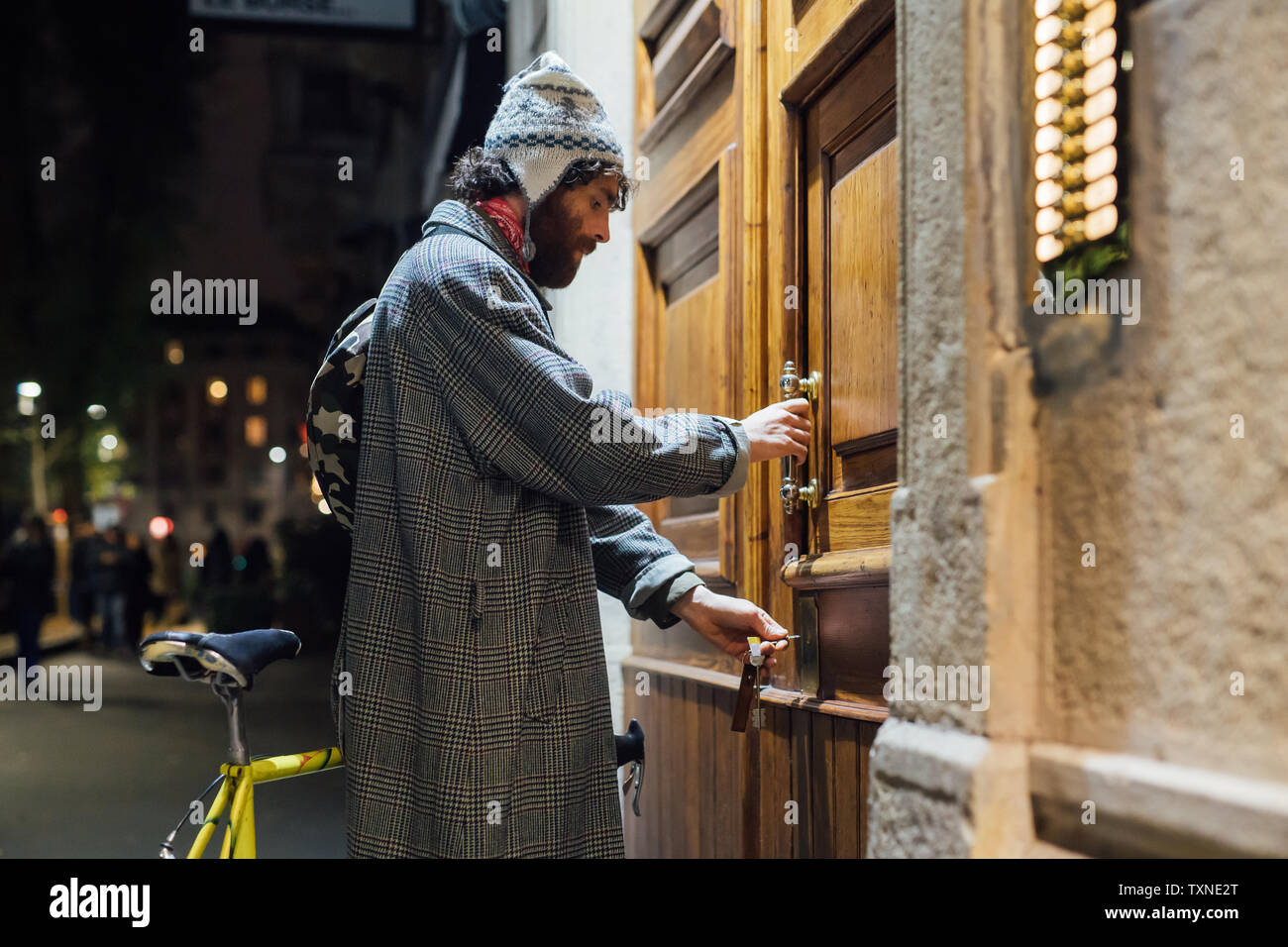 Bearded young man opening door into apartment building Stock Photo
